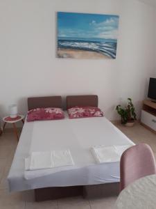 a white bed in a room with a picture of the ocean at Apartments by the sea Kustici, Pag - 6320 in Kustići