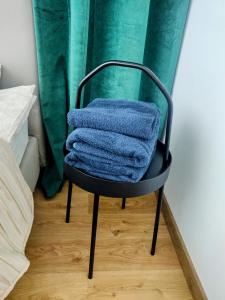 a pile of towels sitting on a chair in a bedroom at Zielony apartament z widokiem na jezioro in Złotów