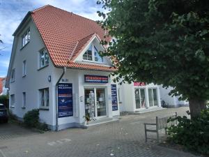 a white building with a red roof on a street at Ferienwohnung P5 in Graal-Müritz