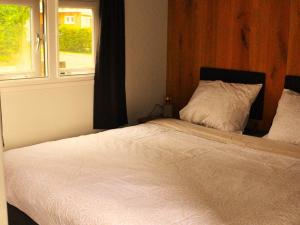 1 cama en un dormitorio con ventana en Serene chalet in Haulerwijk with enclosed garden and views, en Haulerwijk