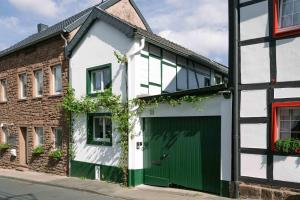 a white house with a green door and a brick building at Gemütliches Fachwerkhaus im Herzen Nideggens in Nideggen