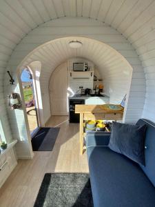 a living room with a blue couch and a kitchen at Finest Retreats - Jam First Cabin in East Looe