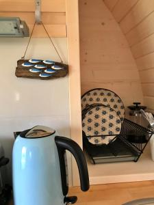a tea kettle and plates on a shelf in a kitchen at Finest Retreats - Prosecco Cabin in East Looe