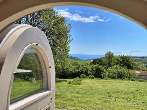 an arched window with a view of a field at Finest Retreats - The Pilchard Cabin in East Looe