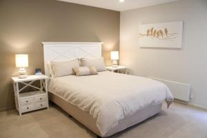 a bedroom with a white bed and two night stands at La mer in Inverloch