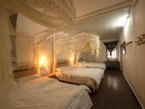 1 dormitorio con 2 camas con sábanas blancas en Yangshuo Loong Old House en Yangshuo