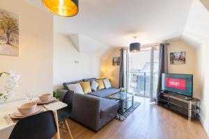 uma sala de estar com um sofá e uma televisão em Velvet 1-bedroom penthouse, Clockhouse, Hoddesdon em Hoddesdon