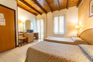 a hotel room with two beds and a desk at Albergo Ristorante Leon d'Oro in Este