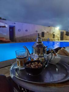 a tray with a tea kettle and a cup of nuts at Riad Hotel Les Flamants in Merzouga