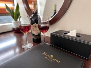 two glasses of wine on a counter with a bottle of wine at Elysinam Boutique Hotel Ha Long in Ha Long