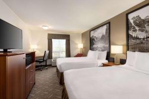 a hotel room with two beds and a flat screen tv at Super 8 by Wyndham Calgary Shawnessy Area in Calgary