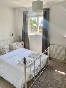 Cheerful 2-bedroom home with free parking في Roughhill: غرفة نوم بسرير ابيض ونافذة