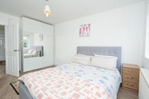 a white bedroom with a bed and a mirror at Modern 2-bedroom flat near Chelsea in London