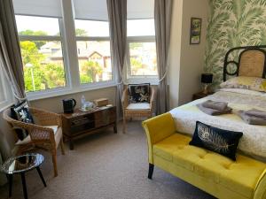 ein Schlafzimmer mit einem Bett und einem gelben Sofa in der Unterkunft San Brelade in Paignton