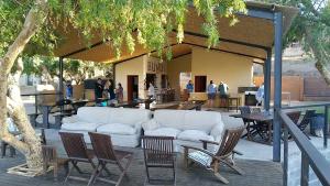un patio con un sofá blanco, sillas y mesas en Bundi Orange River Camp, en Noordoewer
