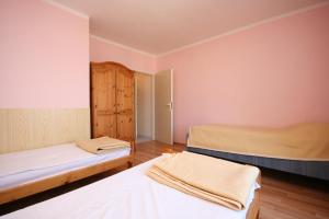 two beds in a room with pink walls and wooden floors at Apartment Stara Novalja 6319f in Stara Novalja