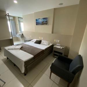 Onix Hotel Aeroporto في لورو دي فريتاس: غرفة نوم فيها سرير وكرسي