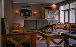 a living room with a couch and tables and a tv at Silk Route Lodge in Gulmit
