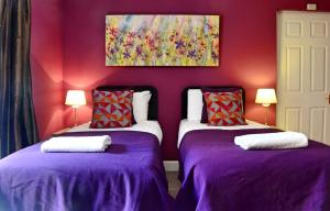 2 camas en una habitación con paredes moradas en ALTIDO Charming 3 bed flat in Haymarket, private parking and patio, en Edimburgo