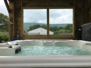 a large bath tub with a view of a barn at Stunning railway carriage with private hot tub in Hereford