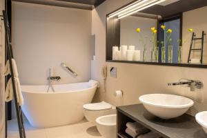 a bathroom with a tub and a toilet and a sink at Hotel Bergs Suites in Rīga