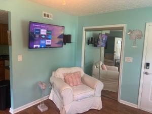 a living room with a chair and a tv on the wall at Cheerful two bedroom house 1.5 miles from beach. in Myrtle Beach