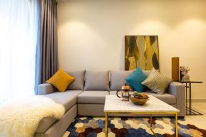 a living room with a gray couch with colorful pillows at Oui! Oui! CBD Apartment - Rivergate Building in Ho Chi Minh City
