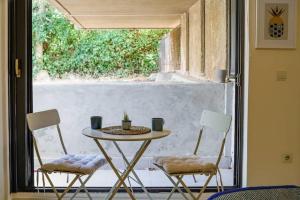 a table and two chairs in front of a window at Studio Krinon - Paleo Psychiko in Athens