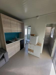 a kitchen with white cabinets and a sink and a refrigerator at Kamp Katra Mobilna hiška ECO in Vinica +16 photos