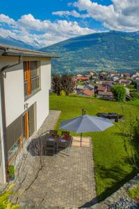eine Terrasse mit einem Tisch und einem Sonnenschirm in der Unterkunft Panoram'Alp in Savièse