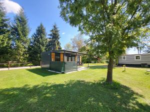 a tiny house in a yard with a tree at Kamp Katra Mobilna hiška ECO in Vinica
