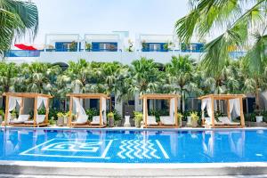 una piscina con sedie a sdraio e palme di Risemount Premier Resort Da Nang a Da Nang