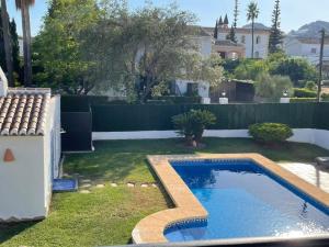 einen Hinterhof mit einem Pool und einem Zaun in der Unterkunft La Renda Mediterranean Villa - Beach and City Center are only 5 minutes walk away in Jávea