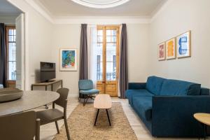 Aspasios Gracia Apartments في برشلونة: غرفة معيشة مع أريكة زرقاء وطاولة
