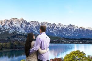 a man and a woman standing next to a lake at Swiss-Belsuites Pounamu Queenstown in Queenstown