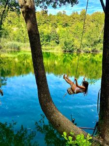 una mujer balanceándose sobre una cuerda columpiándose sobre un lago en Mrežnica - Zelena oaza en Generalski Stol