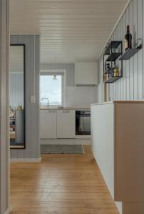 a kitchen with white cabinets and a wooden floor at Cozy 2-bedroom house with a fantastic view in Leynar