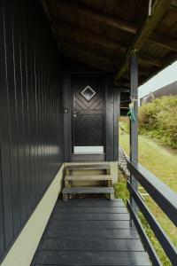 a black front door of a house with stairs at Cozy 2-bedroom house with a fantastic view in Leynar