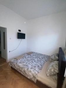 a bed in a room with a television on the wall at Apartmani Home in Zaječar