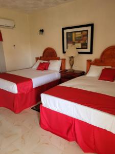 two beds in a hotel room with red and white sheets at Eliwes Villa in Treasure Beach