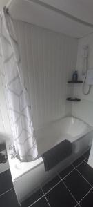a white bath tub with a shower curtain in a bathroom at 6-min Walk to New Cross Parking Long Stay Discounts in Fallings Park