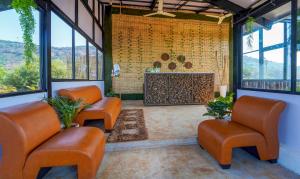 a waiting room with orange chairs and a fireplace at Vee Resort- The Suites of Royals in Mahabaleshwar