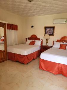 a hotel room with two beds with red sheets at Eliwes Villa in Treasure Beach