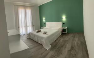 a bedroom with a white bed and green walls at Residenza “La Vecchia Ancora” in Castelsardo