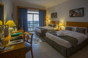 a hotel room with two beds and a desk at Atana Khasab Hotel in Khasab