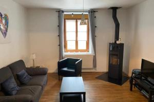 Una sala de estar con un sofá y una estufa de leña. en House With Terrace Near The Lake Gérardmer, en Gérardmer
