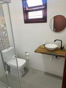 a bathroom with a toilet and a sink and a mirror at Casinhas Terõ - in São Sebastião