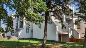 a white building with trees in front of it at Apartamentai įsikūrę Šventojoje in Palanga
