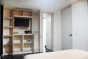 a bedroom with a bed and a tv and shelves at Espectacular apt 3 habitaciones deluxe! in Envigado