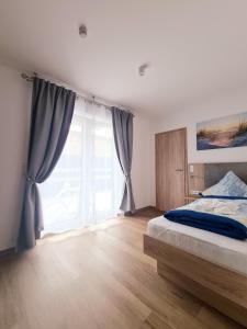 a bedroom with a bed and a large window at Hotel Pension Nordzeit in Norddeich